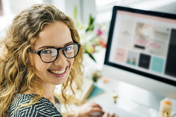 Mulher sorrindo na frente da tela do computador - investir em inbound marketing